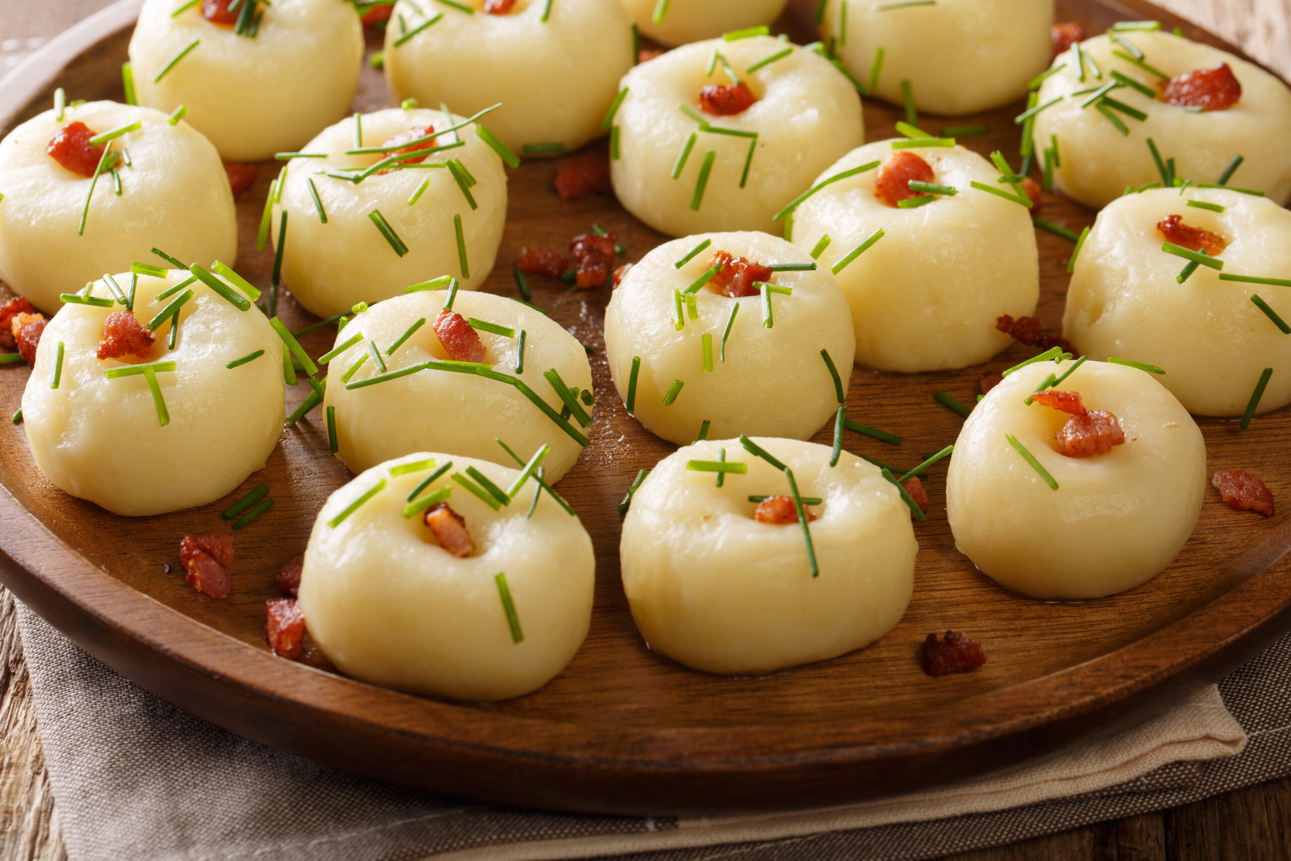 Polish authentic kluski potato dumplings with bacon and green onions close-up on a plate on the table. horizontal