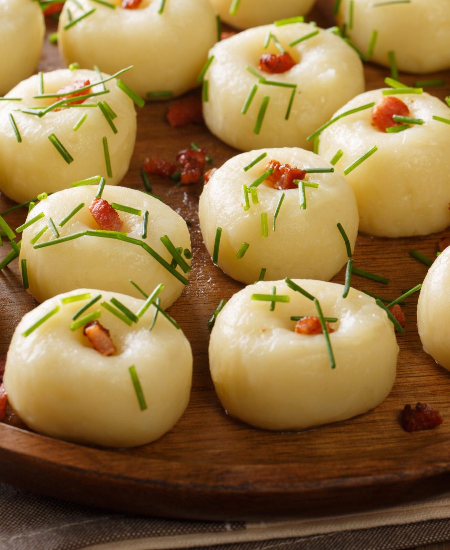 Polish authentic kluski potato dumplings with bacon and green onions close-up on a plate on the table. horizontal
